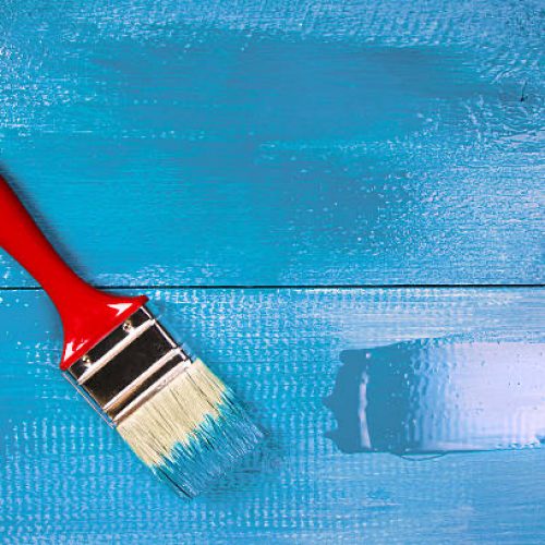 Painting a wooden shelf using paintbrush, blue color